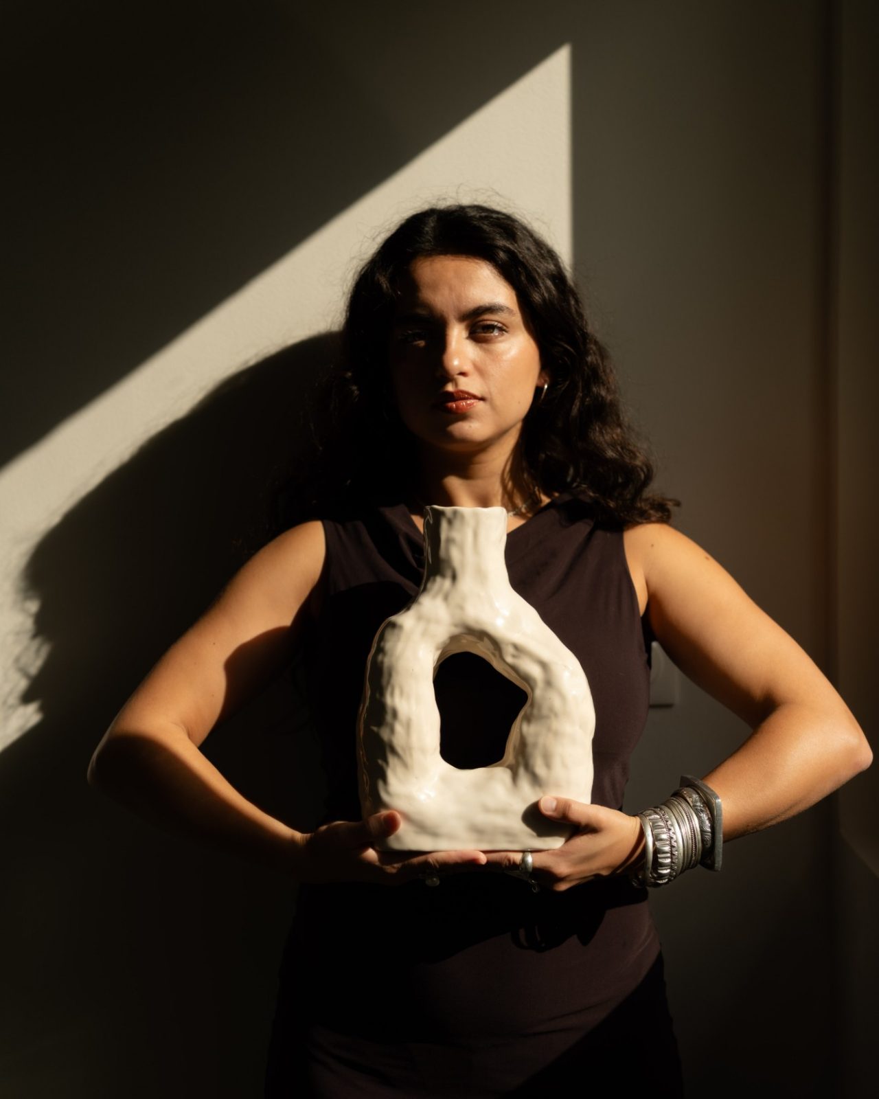 Marie D’Antoni tenant un vase en céramique blanc, dans un rayon de soleil