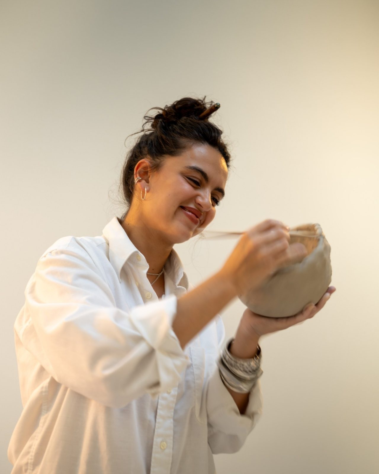 Marie D’Antoni, souriante, en train de modeler un bol en terre
