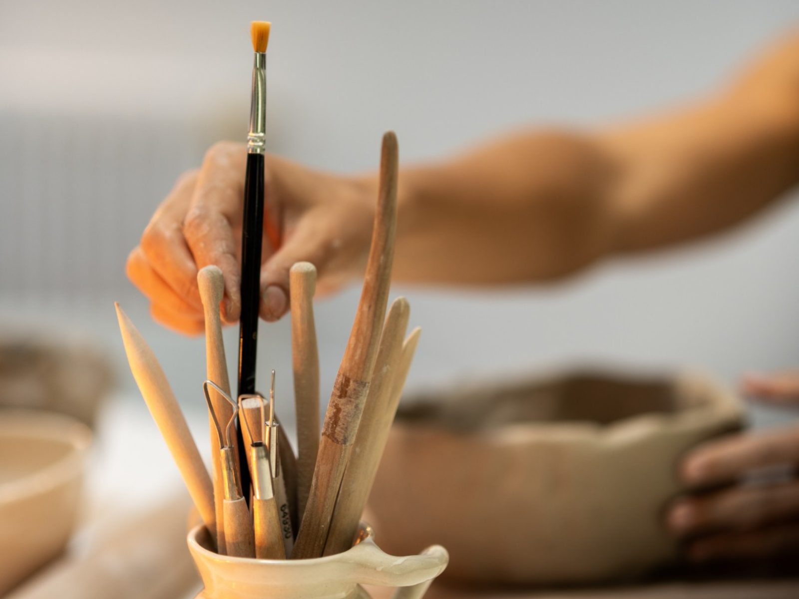 Outils de modelage dans un pichet en céramique, pendant un atelier